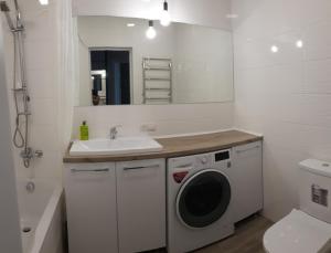 uma casa de banho com uma máquina de lavar roupa e um lavatório em Чудова квартира в центрі міста em Rivne