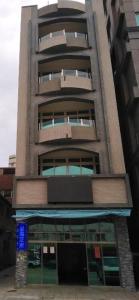 a tall building with a blue sign in front of it at 星海芝家民宿Samuel's Home in Nangan