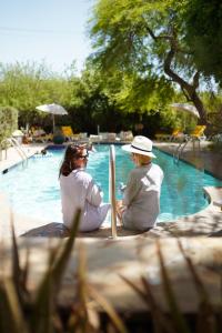 沙漠溫泉的住宿－The Good House- Hot Spring Hideaway，两个女人坐在游泳池旁边