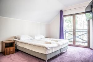 a bedroom with a bed and a large window at Apartamenty Niegocin in Wilkasy