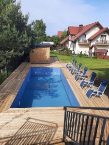 a swimming pool with chairs on a wooden deck at Azymut in Jarosławiec