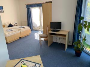 a room with a bed and a desk with a computer at Hotel Pension Neptun in Ueckeritz
