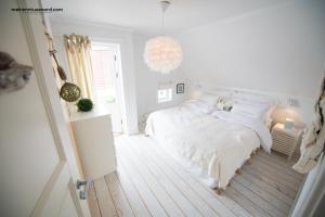 KalvågにあるKalvåg Holidayapartmentの白いベッドルーム(ベッド1台、シャンデリア付)