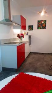 a kitchen with red cabinets and a vase of flowers at House in The Calm Nature of Prosecco Valley in Revine Lago