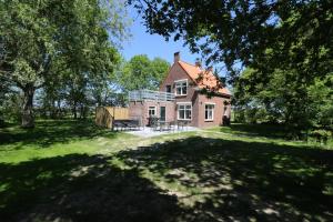 a house in the middle of a yard with trees at Hof Suzanna in Arnemuiden