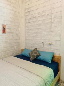 a bed with blue pillows in a bedroom at KALINDA HOMEY in Karimunjawa