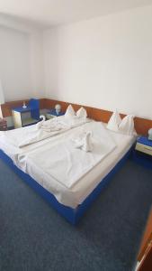 1 cama grande con sábanas blancas y almohadas. en Hotel Banat, en Olimp