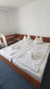 a large white bed with white sheets and pillows at Hotel Banat in Olimp
