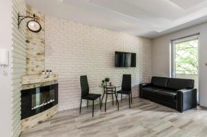 a living room with a black leather couch and a brick wall at Więckowskiego Apartment in Łódź