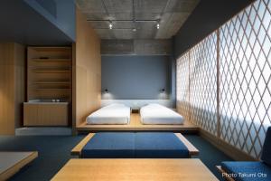 a bedroom with two beds and a projection screen at KUMU Kanazawa by THE SHARE HOTELS in Kanazawa