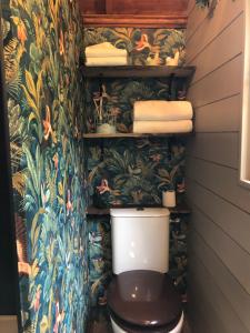a bathroom with a toilet with a tropical wallpaper at Roulotte à Honfleur in Honfleur +11 photos
