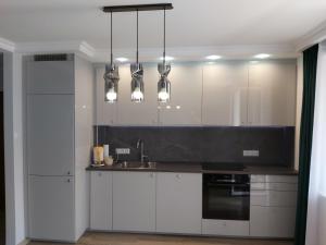 kuchnia z białymi szafkami, zlewem i lampkami w obiekcie Apartament 1 SUPER VIP Królewiecka centrum w mieście Mrągowo +12 zdjęć