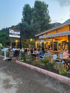 eine Gruppe von Personen, die vor einem Restaurant an Tischen sitzen in der Unterkunft Kara Kedi Beach Bungalow in Cıralı