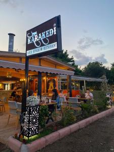 Leute, die vor einem Restaurant an Tischen sitzen in der Unterkunft Kara Kedi Beach Bungalow in Cıralı