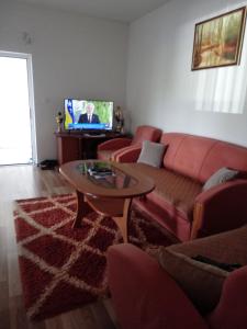 ein Wohnzimmer mit einem Sofa, einem Tisch und einem TV in der Unterkunft Apartman Meka in Sarajevo