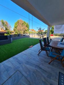 a patio with chairs and a table and a lawn at Apartman Nicolle in Krk