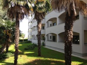 an apartment building with palm trees in front of it at Hotel Flores in Poreč