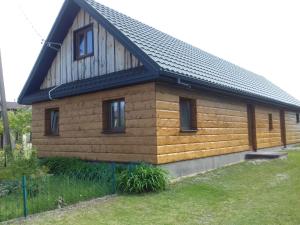 een klein houten huis met een gambrel dak bij Gosciniec in Kodeń