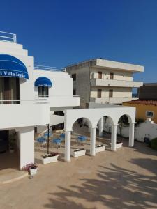 ein weißes Gebäude mit Sonnenschirmen auf einem Parkplatz in der Unterkunft Hotel Villa Ionia in Avola