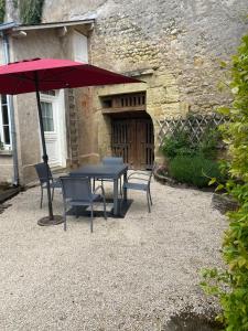 a table and chairs with an umbrella in front of a building at Maîson Vigneronne in Nazelles