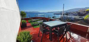 Una mesa y sillas en un balcón con vista al agua. en Casa da Banda, en Bueu