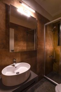 a bathroom with a sink and a shower with a mirror at Konaki Hotel in Papigko
