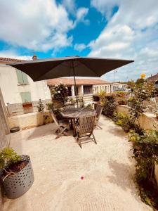 una mesa y sillas bajo una sombrilla en un patio en charmante maison de village renovée, en Bazoges-en-Pareds