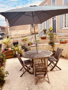 a wooden table with an umbrella and two chairs at charmante maison de village renovée in Bazoges-en-Pareds