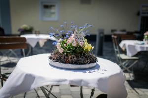 a white table with a flower arrangement on top of it at Gasthaus & Pension Mohren in Pfullendorf