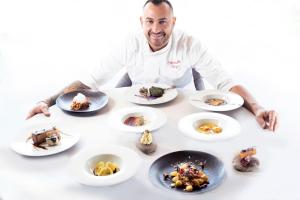 a chef sitting at a table with plates of food at Ciampedie Luxury Alpine Spa Hotel in Vigo di Fassa