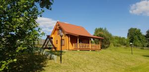 a log cabin with a deck on a grass field at Domek nad jeziorem Ublik in Miłki