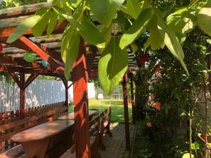 a wooden bench sitting under a wooden pergola at Jesolo Apartmanház in Balatonkeresztúr