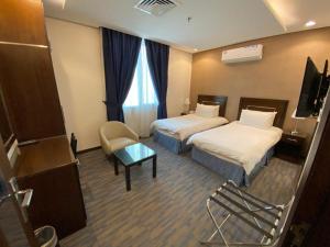 a hotel room with two beds and a chair at Regent Hotel Apartments in Kuwait