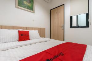 a bedroom with a bed with a red pillow on it at RedDoorz near Seasons City Mall 3 in Jakarta