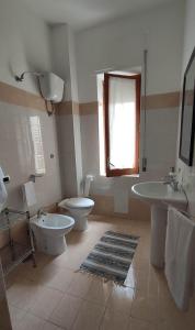 Un baño con dos lavabos y un inodoro y una ventana. en Casa Angela, en Salerno