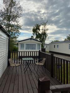a wooden deck with a table and chairs on it at Willerby Grasemere Lochlands Leisure Park Forfar in Forfar
