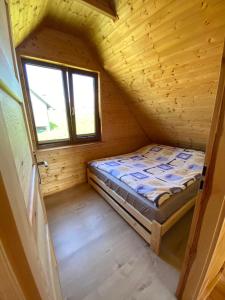 een klein bed in een houten kamer met een raam bij Całoroczny dom letniskowy 2 in Borzestowska Huta