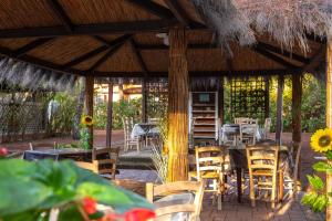 a patio with chairs and tables and a straw umbrella at Camping Village Il Sole in Marina di Grosseto