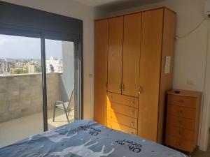 a bedroom with a bed and a dresser and a window at Penthouse In The City in Rechovot