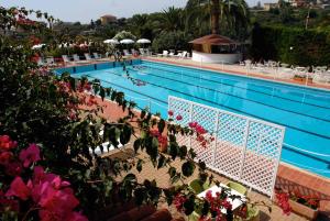 een zwembad met roze bloemen voor het zwembad bij La Locanda Azzurra in Sanremo