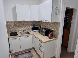 a small kitchen with white cabinets and a microwave at Penthouse In The City in Rechovot