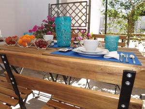 einem Holztisch mit Schalen aus Obst und blauen Gläsern in der Unterkunft La Dimora di Ntò in Villaggio Azzurro
