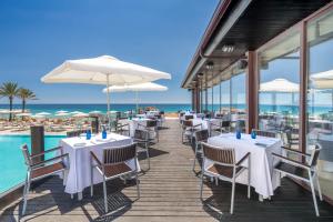 a restaurant on the beach with tables and umbrellas at Hotel Guadalmina in Marbella