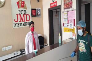twee mensen met gezichtsmaskers aan de toonbank bij Hotel JMD International Katihar in Katihār