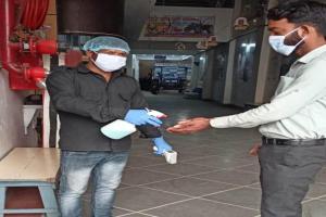 twee mannen met maskers en handschoenen die handen schudden in een gebouw bij Hotel JMD International Katihar in Katihār