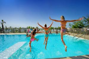 a group of girls jumping into a swimming pool at LES PIEDS DANS L'EAU A PALAVAS ! Mer à 50 m ! MHome 6 Pers climatisé T confort CAMPING 4 ETOILES in Palavas-les-Flots
