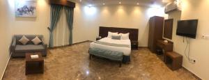 a bedroom with a bed and a chair and a television at توجاردن النهضة - Tu jardin Al Nahda in Jeddah