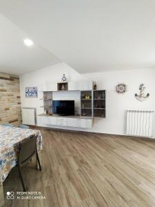 un soggiorno con pareti bianche e pavimenti in legno di Attico Gloria & Greta a Castellammare del Golfo