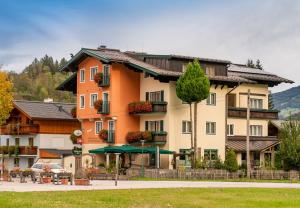 um grande edifício de apartamentos com uma árvore em frente em Hotel Gleimingerhof - Reiteralm em Gleiming