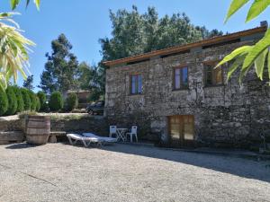 una casa de piedra con una mesa y un banco delante de ella en Casa das Bouças, en Melgaço